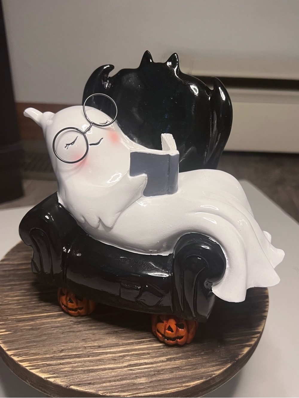 White Ghost Figurine Reading on Black Bat-Back Armchair